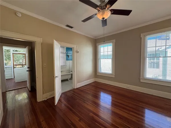a view of empty room with wooden floor and fan