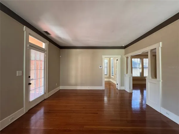 a view of an empty room with wooden floor and a window