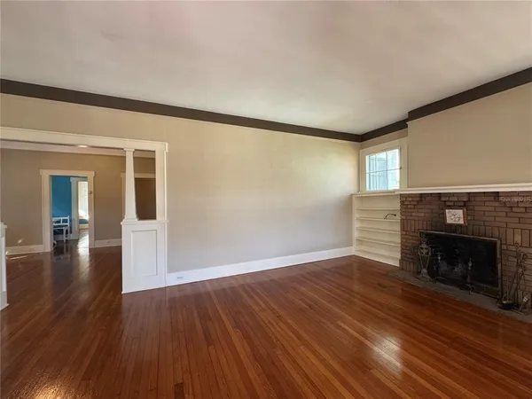 a view of empty room with wooden floor and fireplace