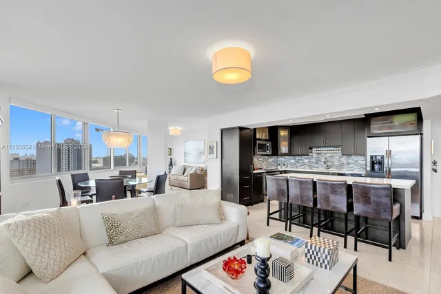 a living room with furniture kitchen view and a large window