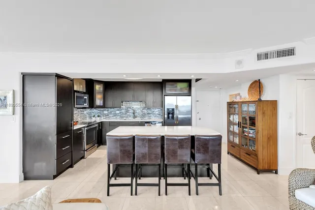 a kitchen with stainless steel appliances kitchen island granite countertop a table chairs sink and cabinets