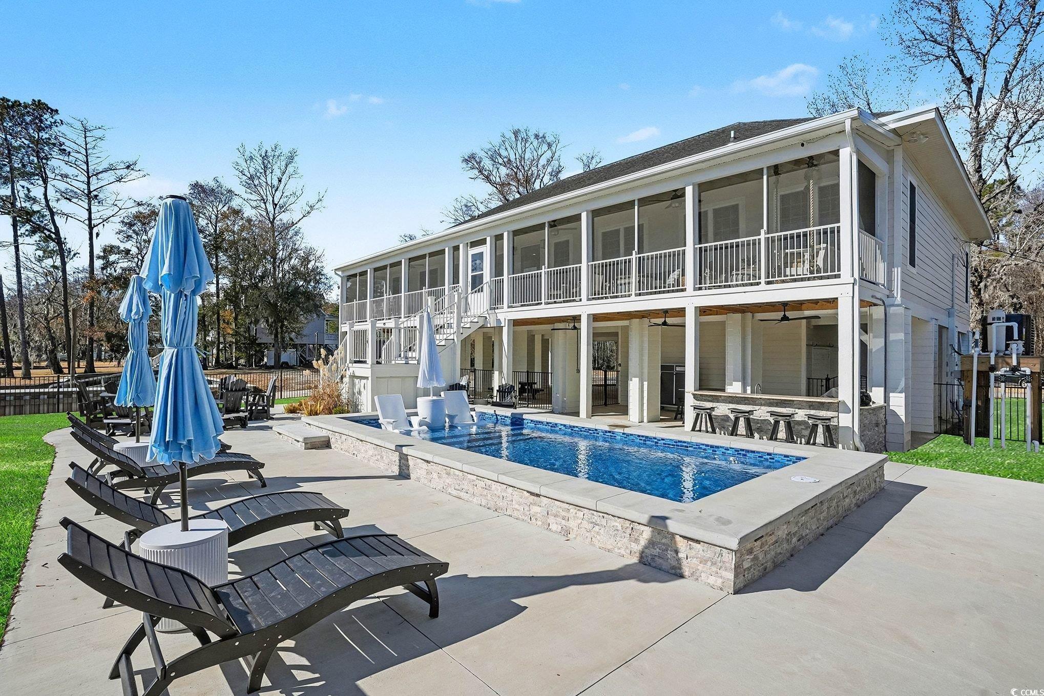 Back of house with a ceiling fan, a patio, a sunroom, and a balcony