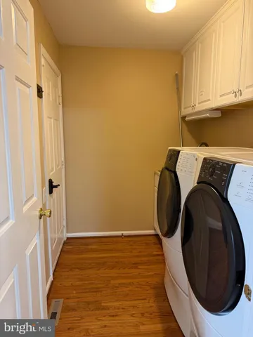 a utility room with wooden floor and washing machine