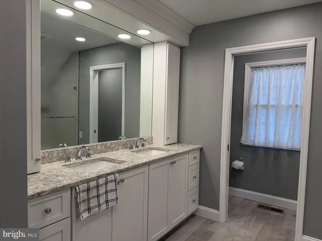 a bathroom with a granite countertop sink a mirror and a shower