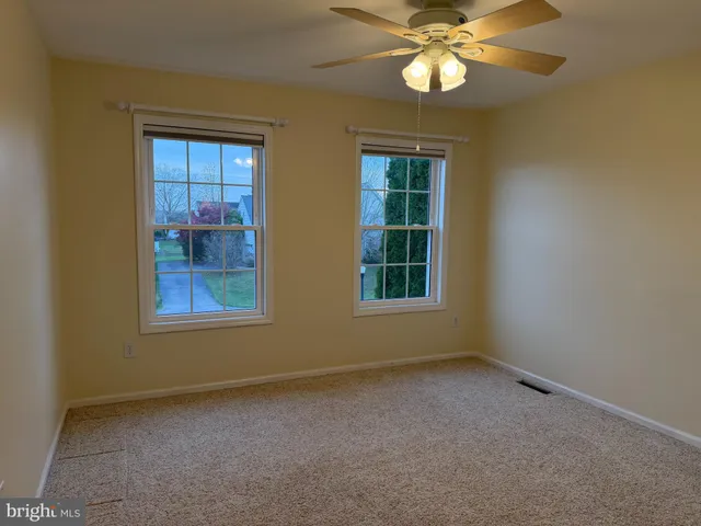 an empty room with a ceiling fan and a window