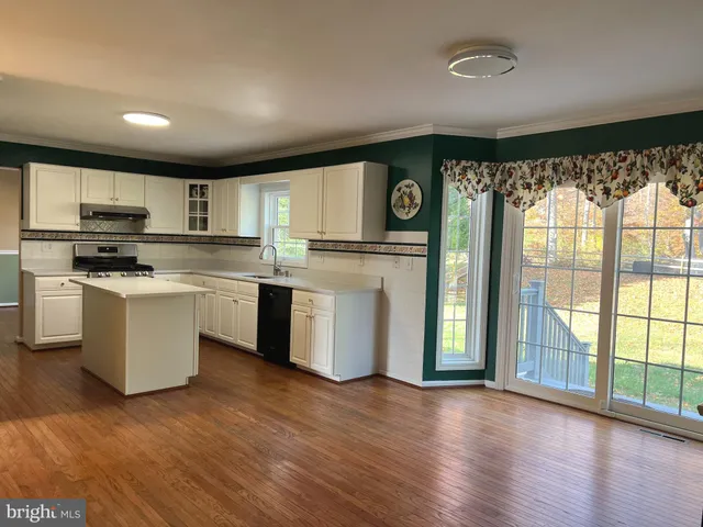 a kitchen with stainless steel appliances wooden floors and white cabinets