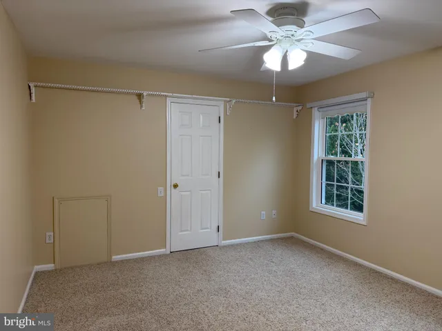 an empty room with a chandelier fan and a bathroom