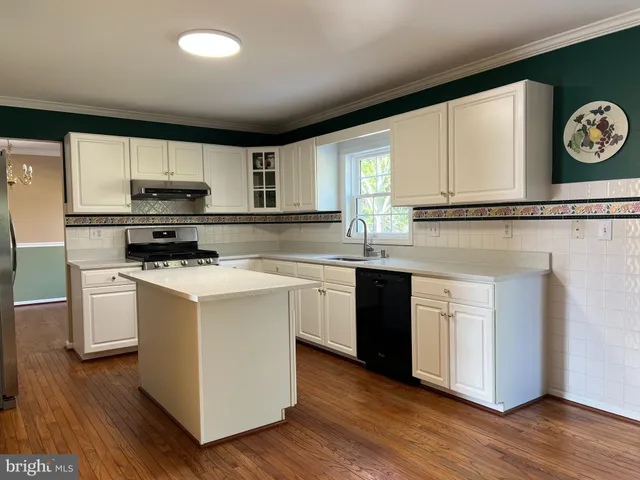 a kitchen with kitchen island granite countertop a stove top oven a sink and cabinets