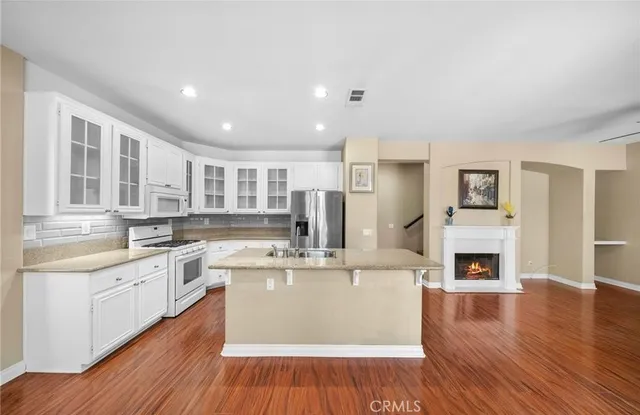 a kitchen with granite countertop a stove a sink and white cabinets