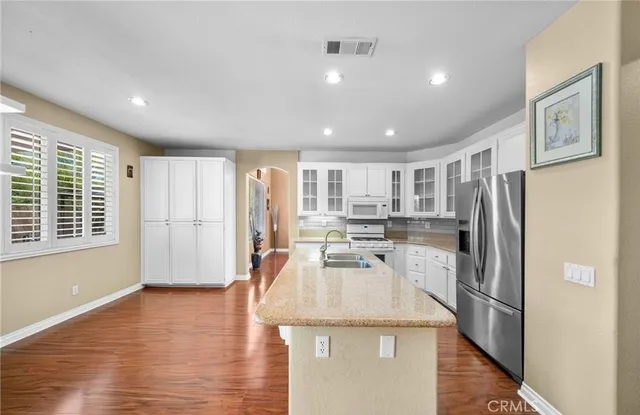 a kitchen with a refrigerator a stove and white cabinets with wooden floor