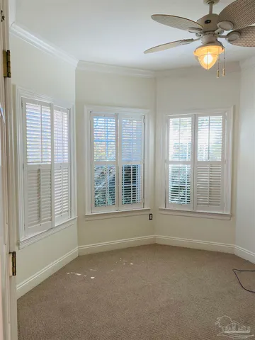 an empty room with windows and fan