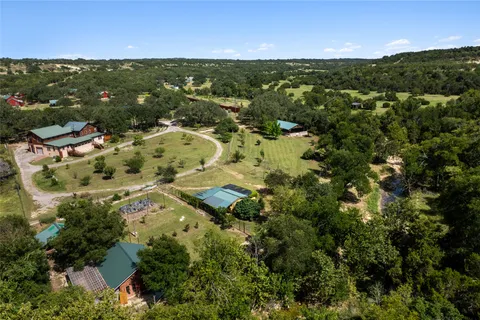 an aerial view of residential houses with outdoor space and trees
