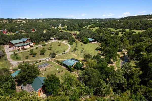 an aerial view of residential houses with outdoor space and trees