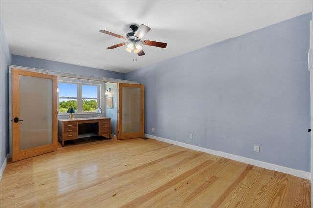 a view of an empty room with window and wooden floor