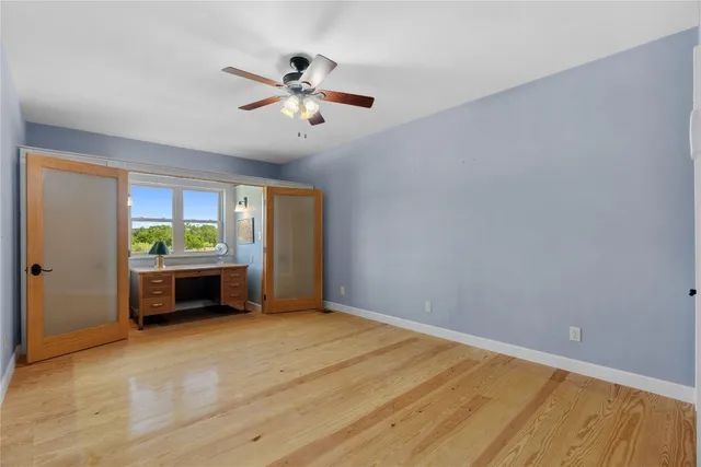a view of an empty room with window and wooden floor