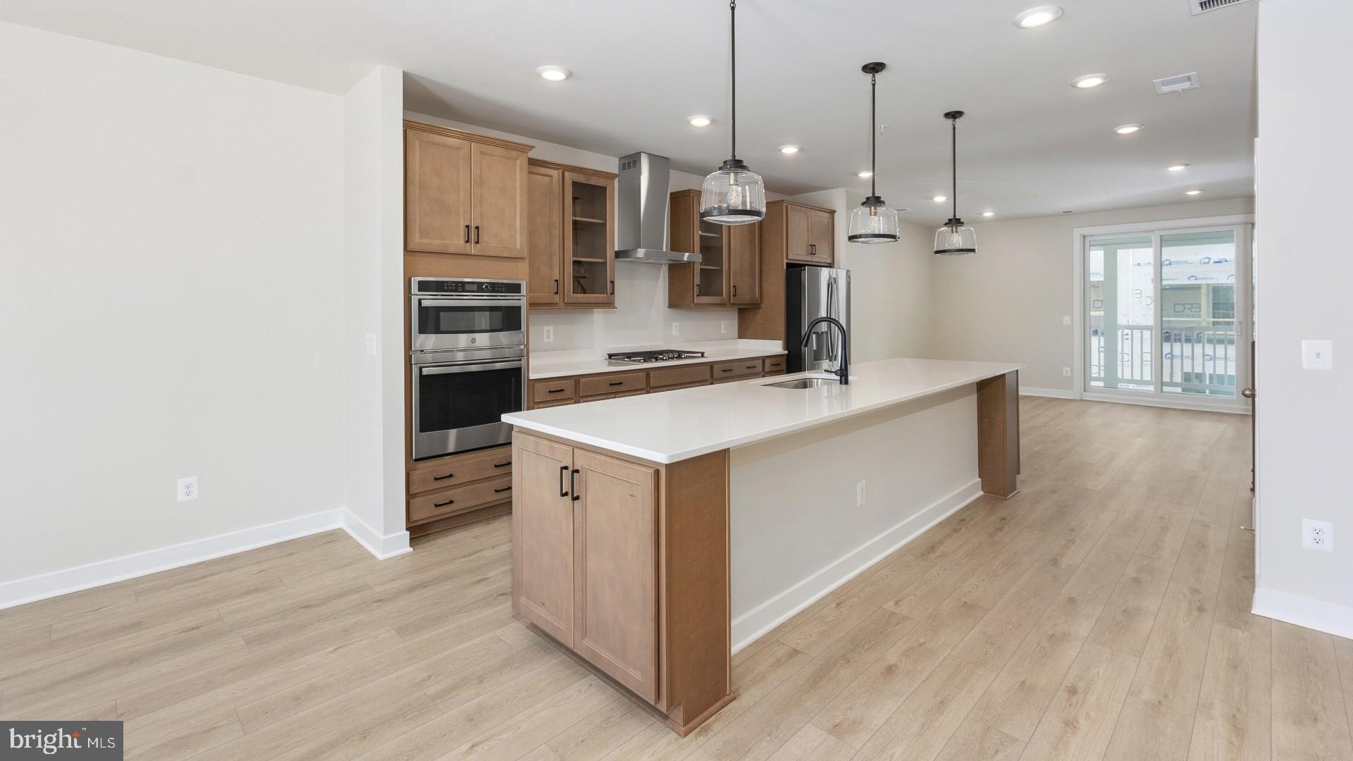 20821 Cloongee Terrace Sterling, VA 20166 - Photo 6 of 34 a large kitchen with stainless steel appliances kitchen island a large counter top and a wooden floors