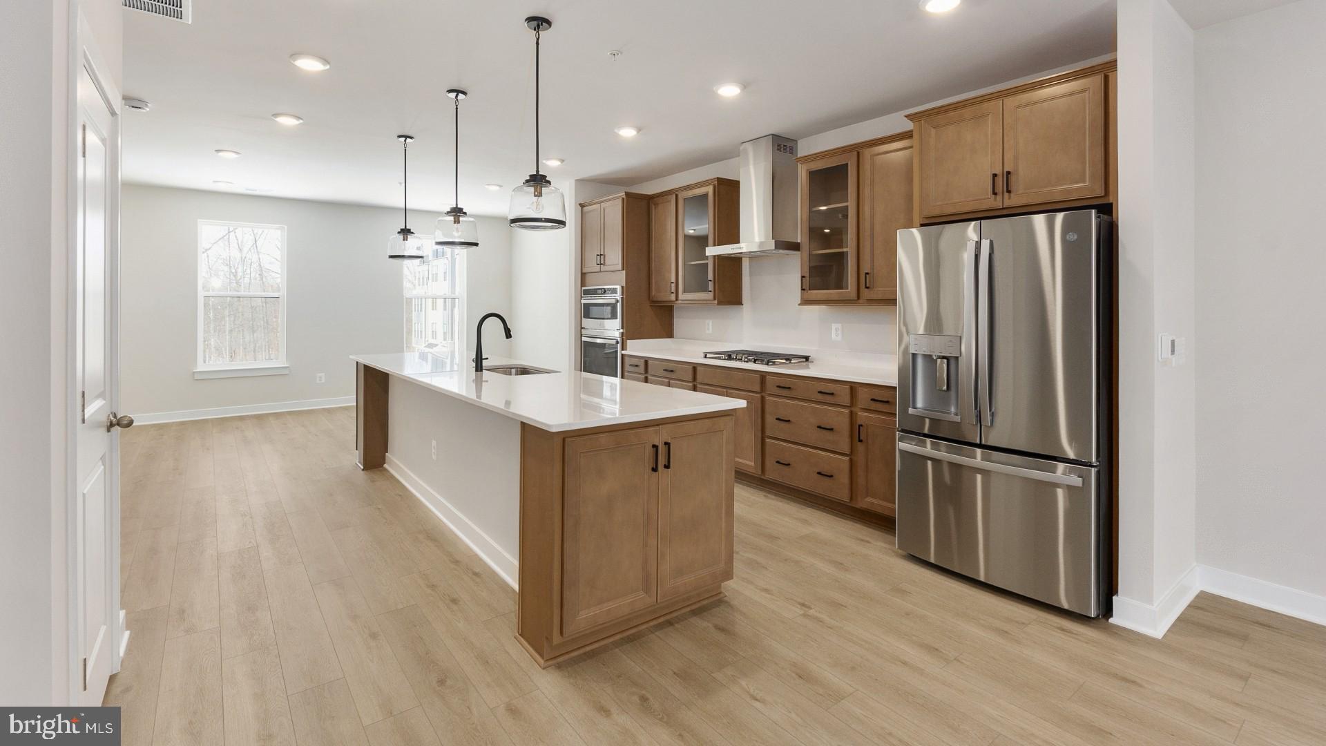 20821 Cloongee Terrace Sterling, VA 20166 - Photo 7 of 34 a kitchen with kitchen island granite countertop a refrigerator oven a sink dishwasher and white cabinets with wooden floor