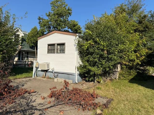 a backyard of a house with large trees and outdoor seating