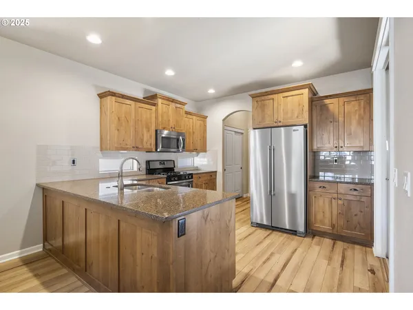 a kitchen with stainless steel appliances granite countertop a refrigerator a sink and a stove
