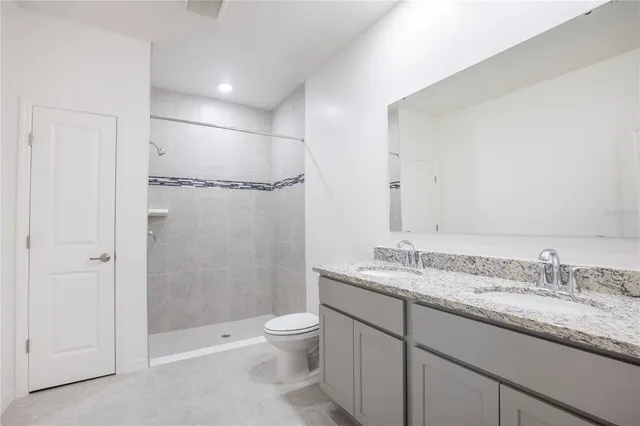 a bathroom with a granite countertop sink a toilet and shower
