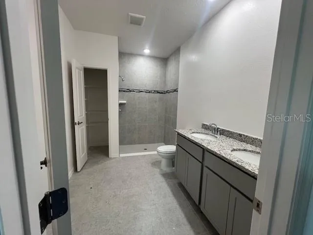 a bathroom with a granite countertop sink a toilet and shower