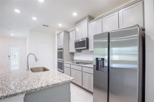 a kitchen with kitchen island granite countertop a sink stainless steel appliances and cabinets