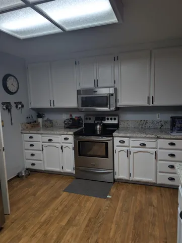 a kitchen with granite countertop a stove top oven microwave and cabinets