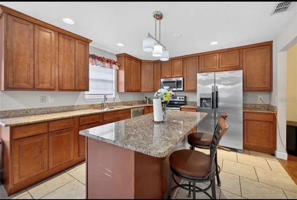 a kitchen with stainless steel appliances granite countertop a sink refrigerator and cabinets