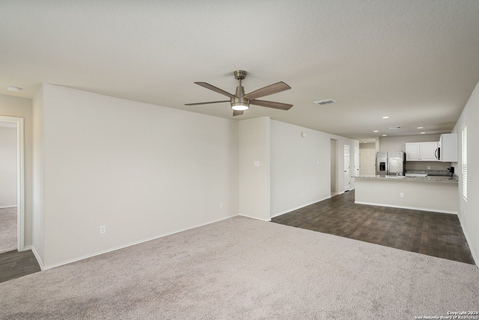 3619 Storm Moon Converse, TX 78109 - Photo 14 of 28 an empty room with a ceiling fan and kitchen view