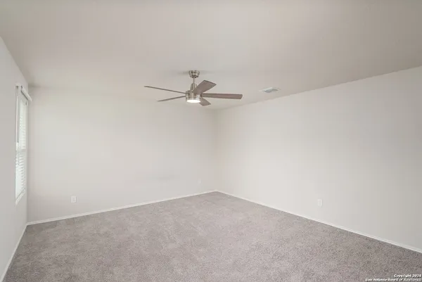 an empty room with a ceiling fan and a window