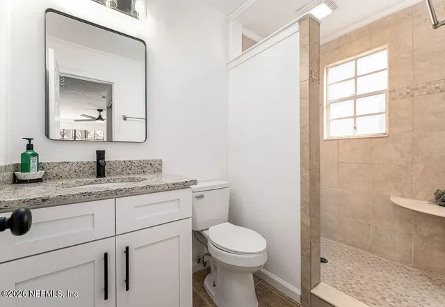 a bathroom with a granite countertop toilet sink and mirror