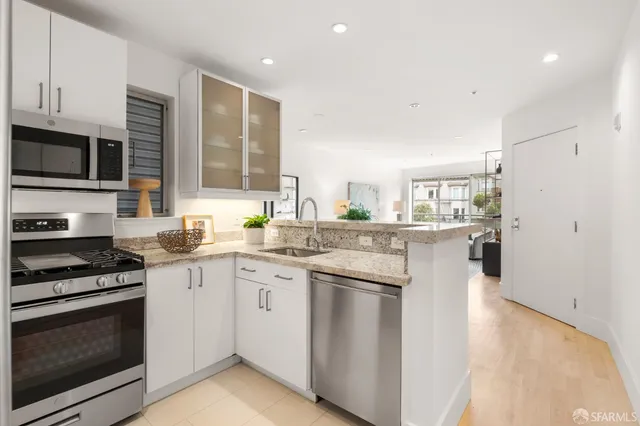 a kitchen with stainless steel appliances granite countertop a stove top oven a sink dishwasher and a refrigerator