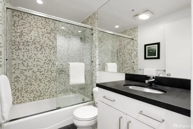 a bathroom with a bathtub shower sink vanity and toilet
