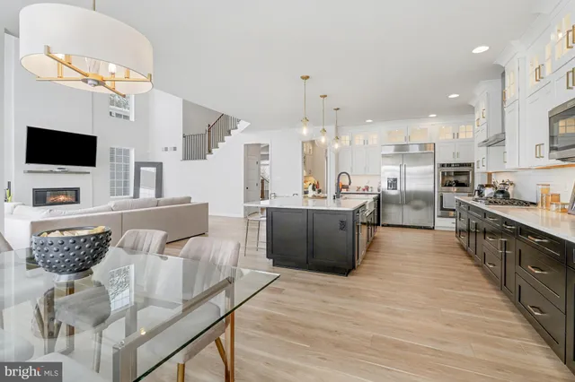 a large living room with stainless steel appliances kitchen island granite countertop a couch and a flat screen tv