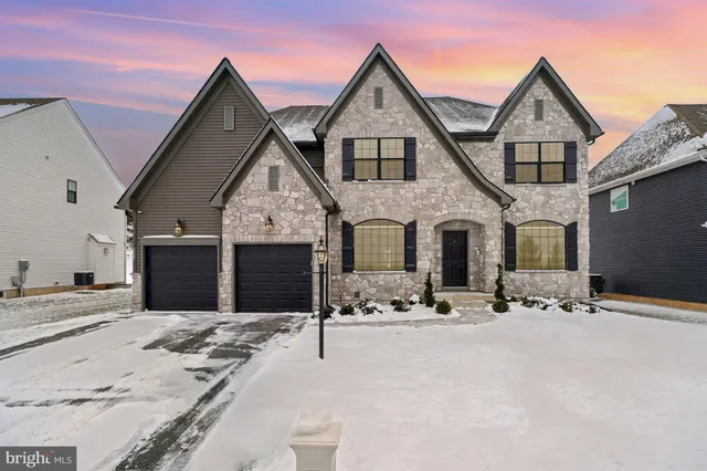 a front view of a house with snow on the road