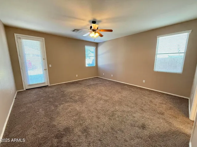 an empty room with windows and chandelier fan