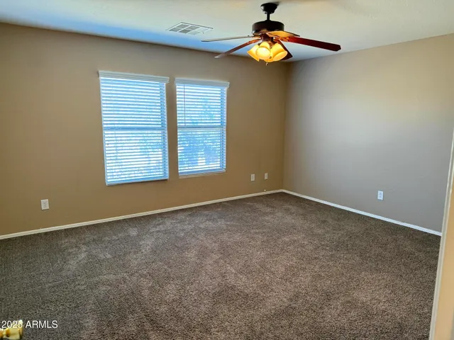 an empty room with windows and chandelier fan