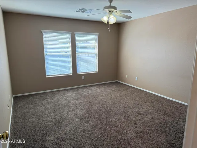 an empty room with windows and chandelier fan