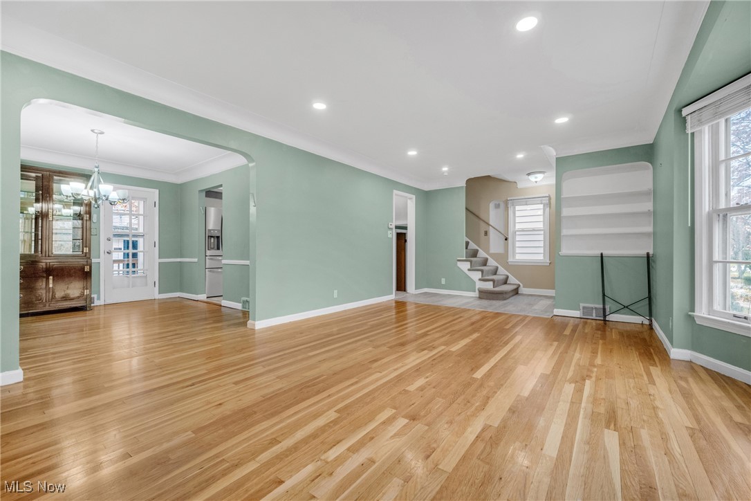4430 Silsby Road Cleveland, OH 44118 - Photo 13 of 43 Unfurnished living room with a wealth of natural light, crown molding, an inviting chandelier, and light wood-type flooring