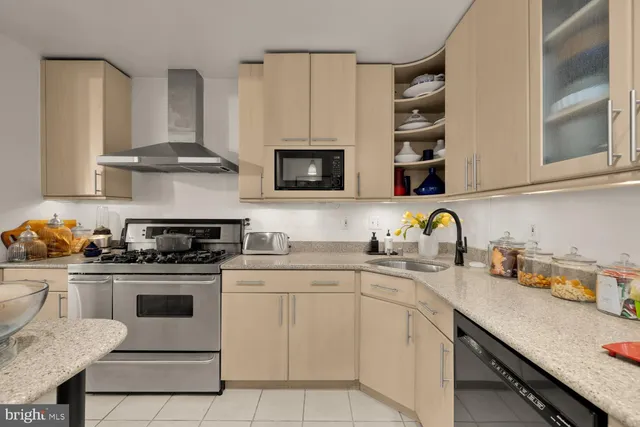 a kitchen with stainless steel appliances granite countertop a stove a sink dishwasher and white cabinets with wooden floor