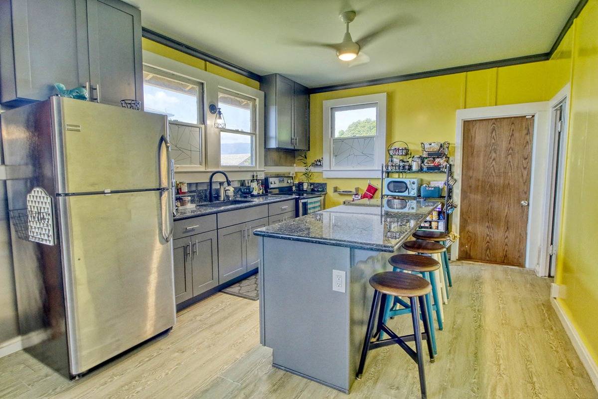 4875 Pelehu Road Kapaa, HI 96746 - Photo 6 of 15 a kitchen with a refrigerator a stove a sink dishwasher and a dining table with wooden floor