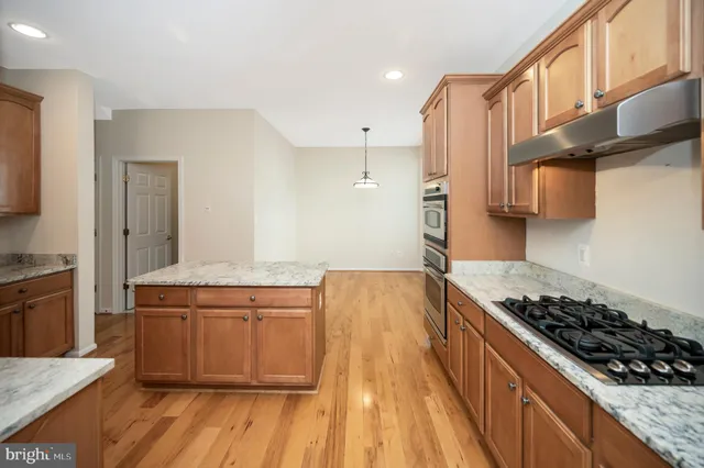 a kitchen with stainless steel appliances granite countertop a refrigerator oven stove with granite countertops and wooden cabinets