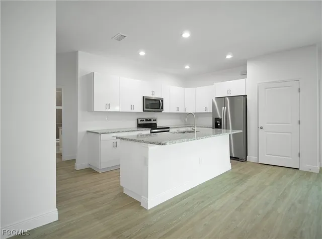 a view of a kitchen with white cabinets and wooden floor