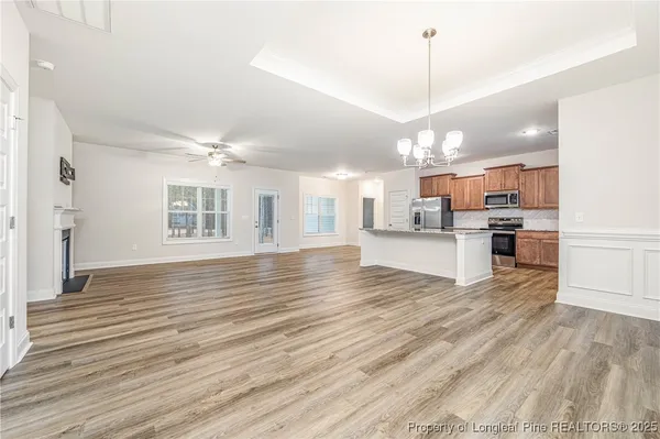 a view of a kitchen with kitchen island a sink wooden floor and a refrigerator