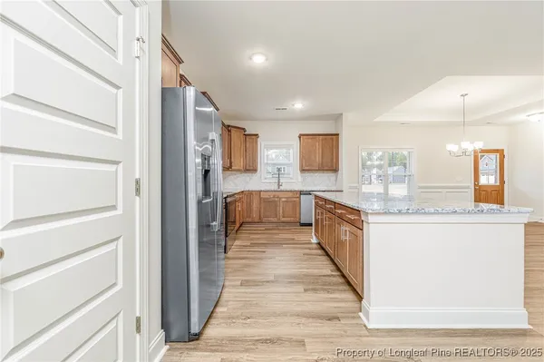 a large white kitchen with granite countertop a large counter top and stainless steel appliances