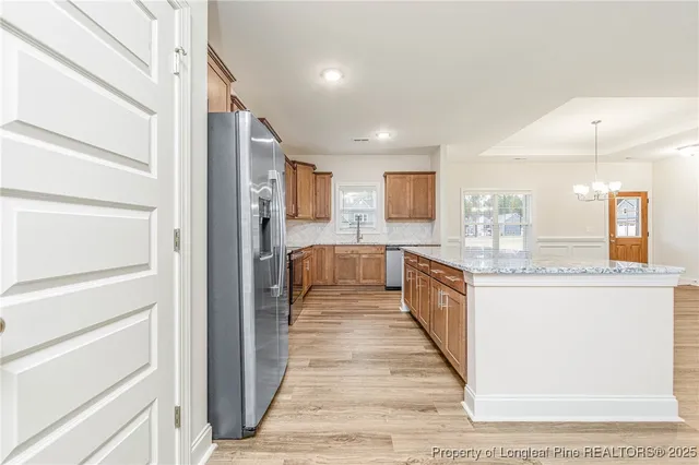 a large white kitchen with granite countertop a large counter top and stainless steel appliances