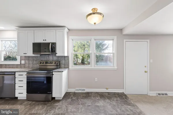 a kitchen with granite countertop a sink cabinets stainless steel appliances and a window