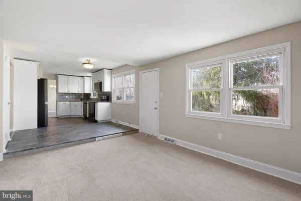 an empty room with wooden floor chandelier and windows
