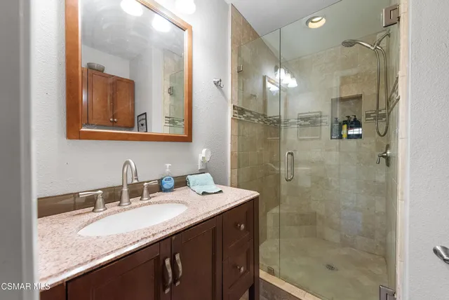 a bathroom with a granite countertop sink mirror and shower