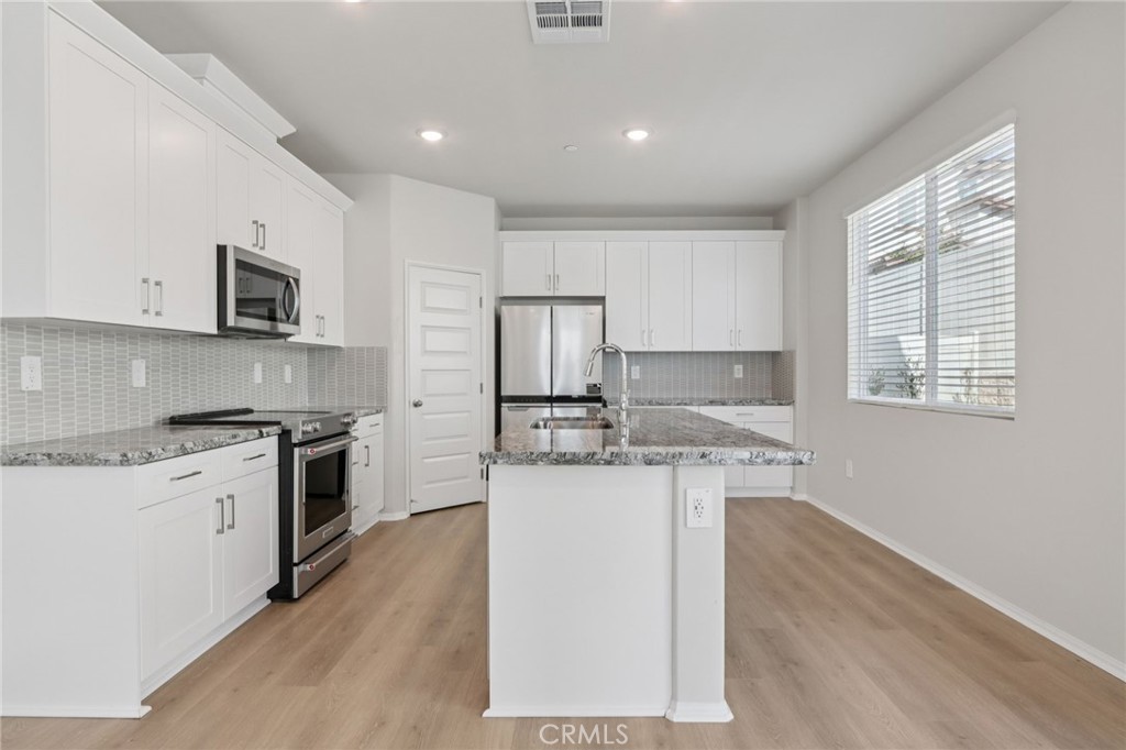 1110 Tropic Court Redlands, CA 92374 - Photo 16 of 44 a kitchen with granite countertop a stove top oven sink and cabinets